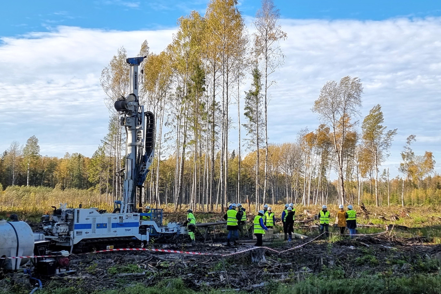 Puurmasin raiesmikul, helkurvestide ja kiivritega inimesed puurmasina juures